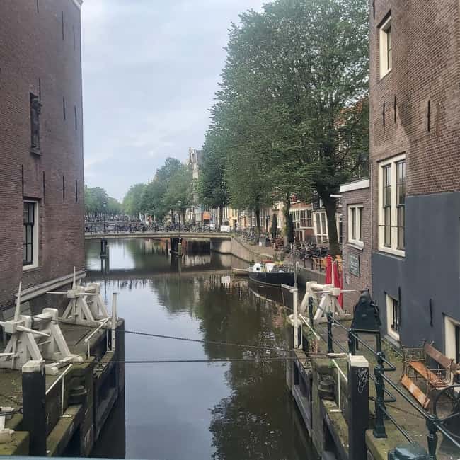 Amsterdam: Spanish Tour Unmasking the Redlight District - Into the Red Light District canal network: Oude Kerk, Oudezijds Voorburgwal, and Warmoesstraat